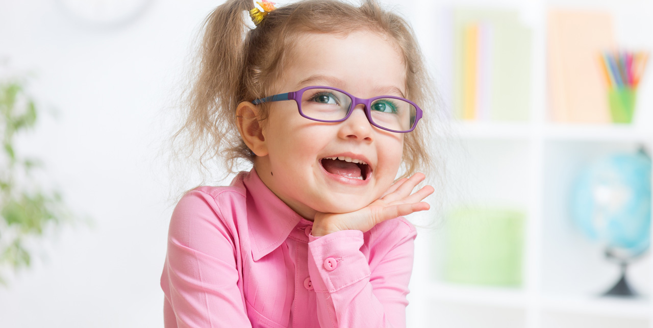 little girl with purple glasses and pink shirt smiling